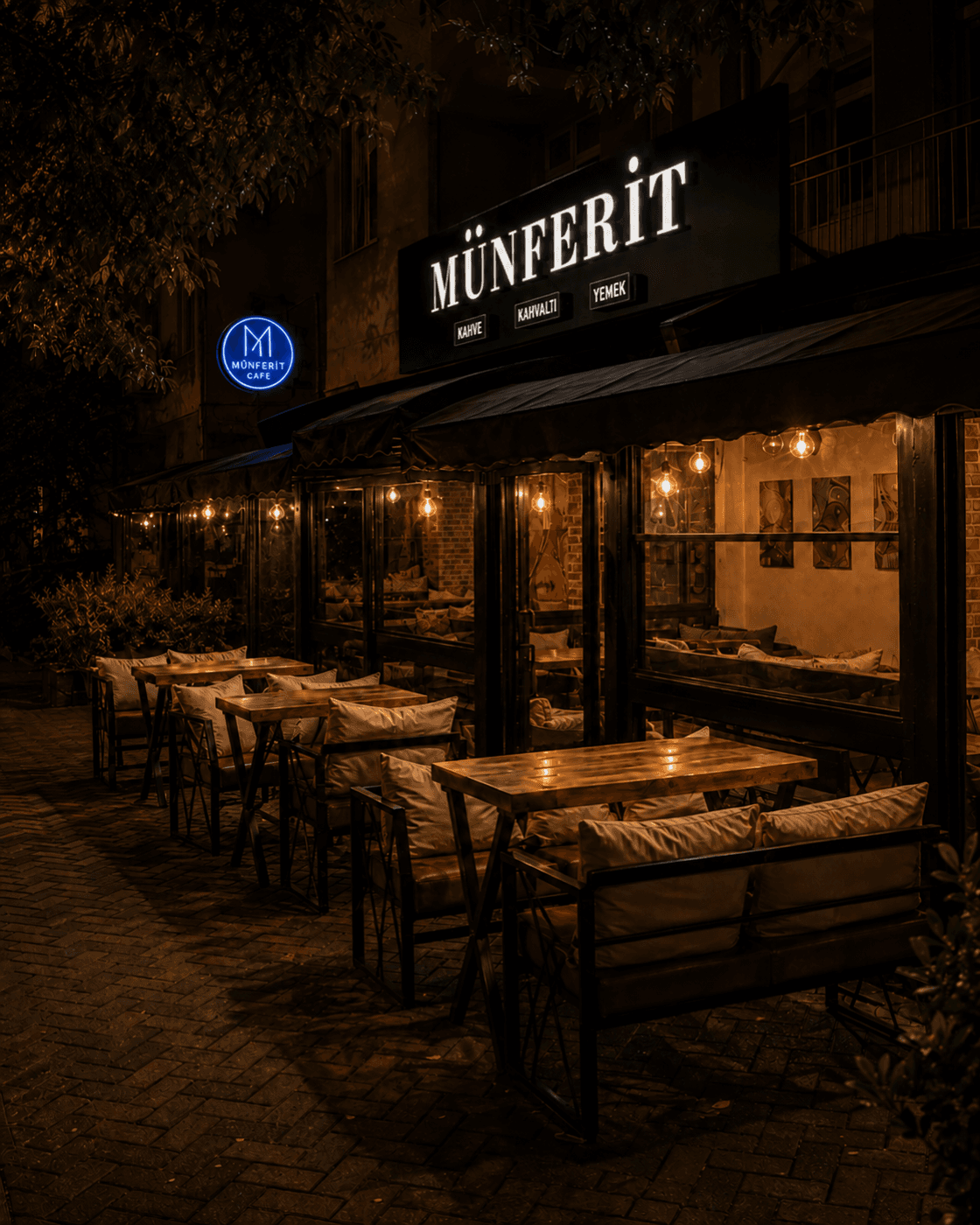 Münferit Cafe'nin akşam saatlerinde ışıklı tabelası, tentesi ve kaldırımdaki oturma alanı